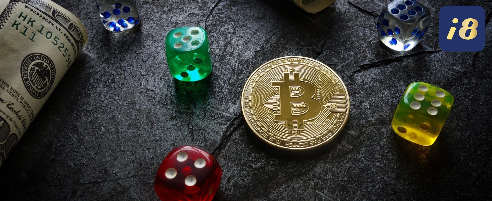 Rolled dollar, Bitcoin coin, and colorful dice on dark textured surface. Blue "i8" logo in the corner, conveying a gambling mood.